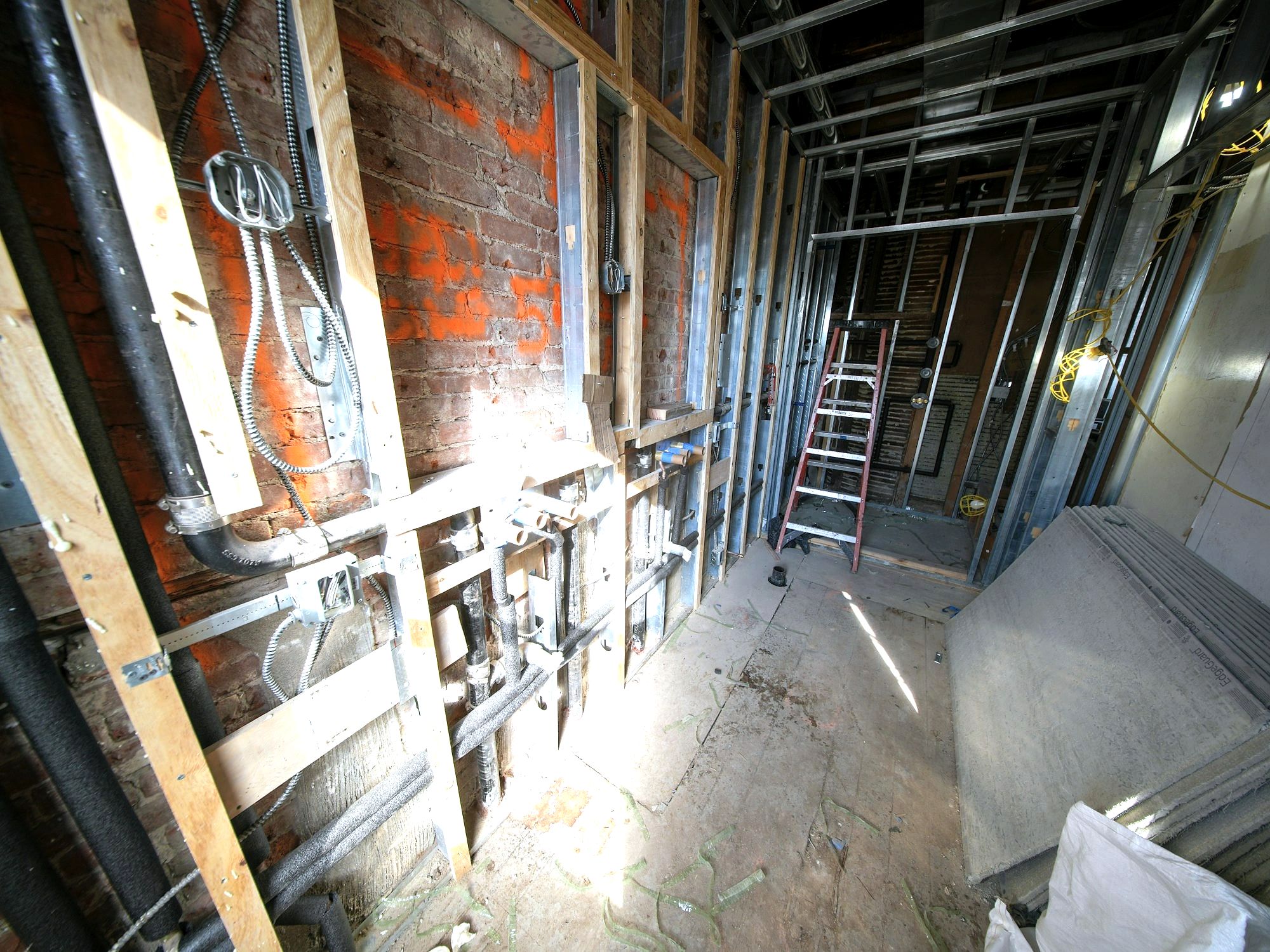 Brick building interior under construction with conduit and ladder